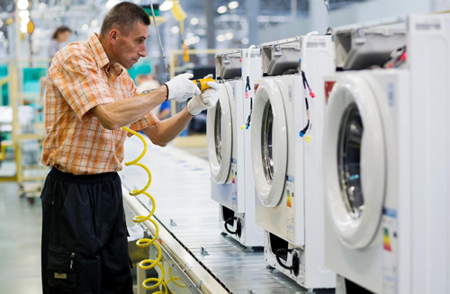 Washing Machine Being Manufactured_Poland Production Facility A male worker assembling the compartments of washing machines at an LG factory