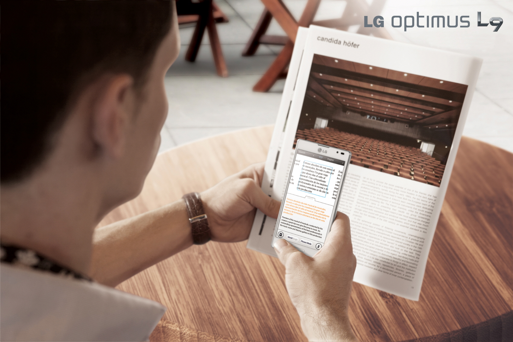 A man is using LG Optimus L9’s QTranslator feature to help him read a magazine