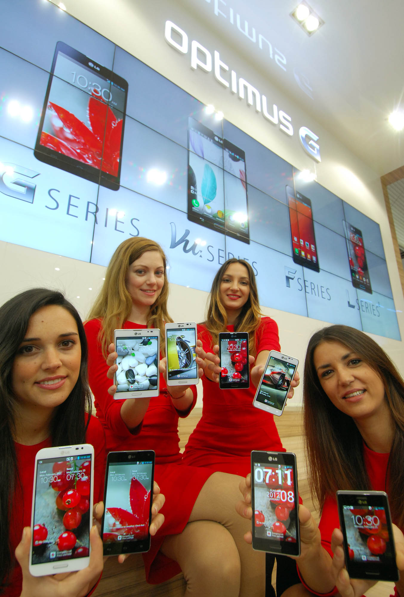 Four female models are smiling at a camera holding various strategic Optimus series devices at MWC 2013 - G, Vu:, F and LII.
