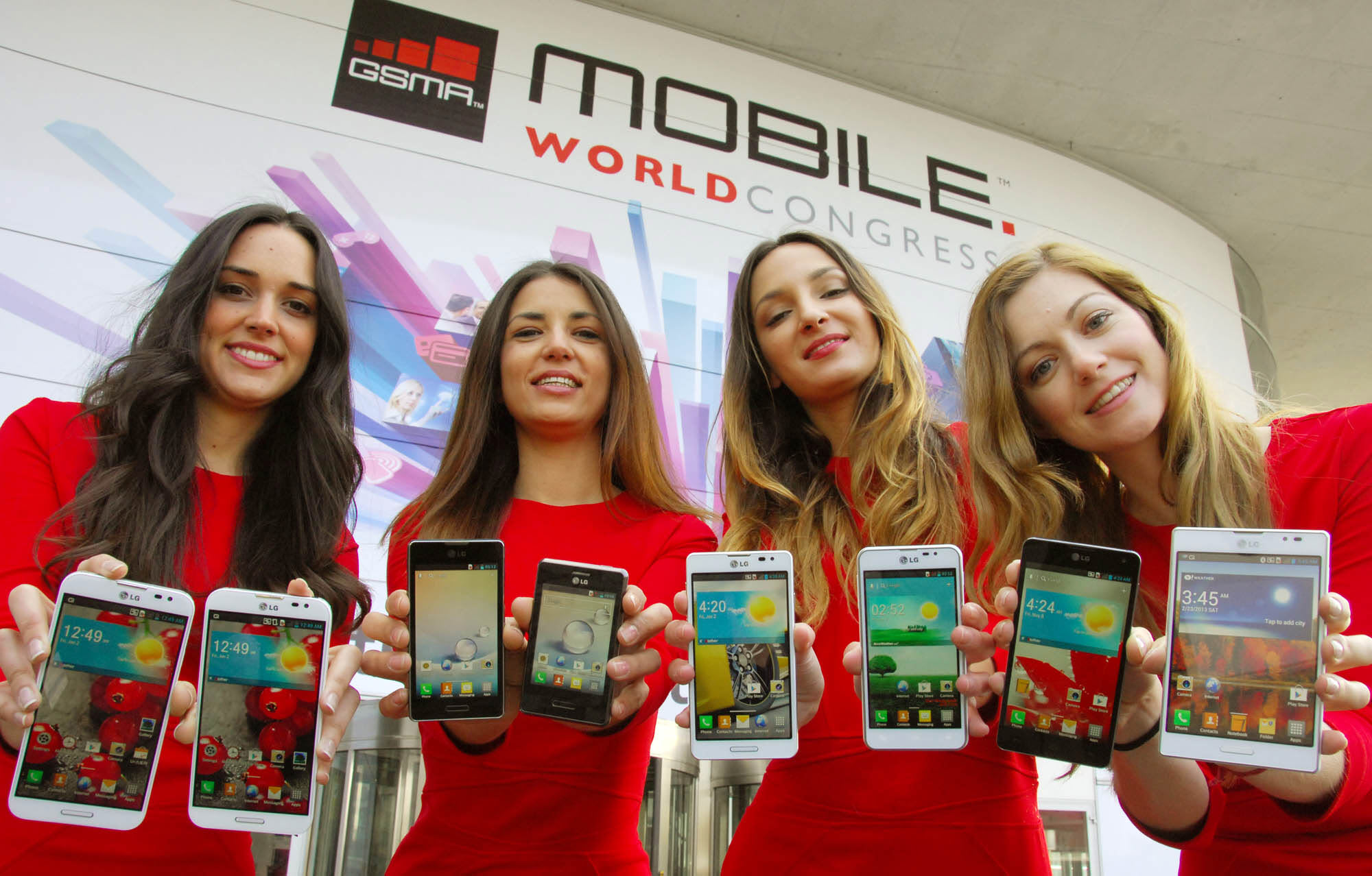 Four female models are smiling at a camera holding various strategic Optimus series devices at MWC 2013 - G, Vu:, F and LII.