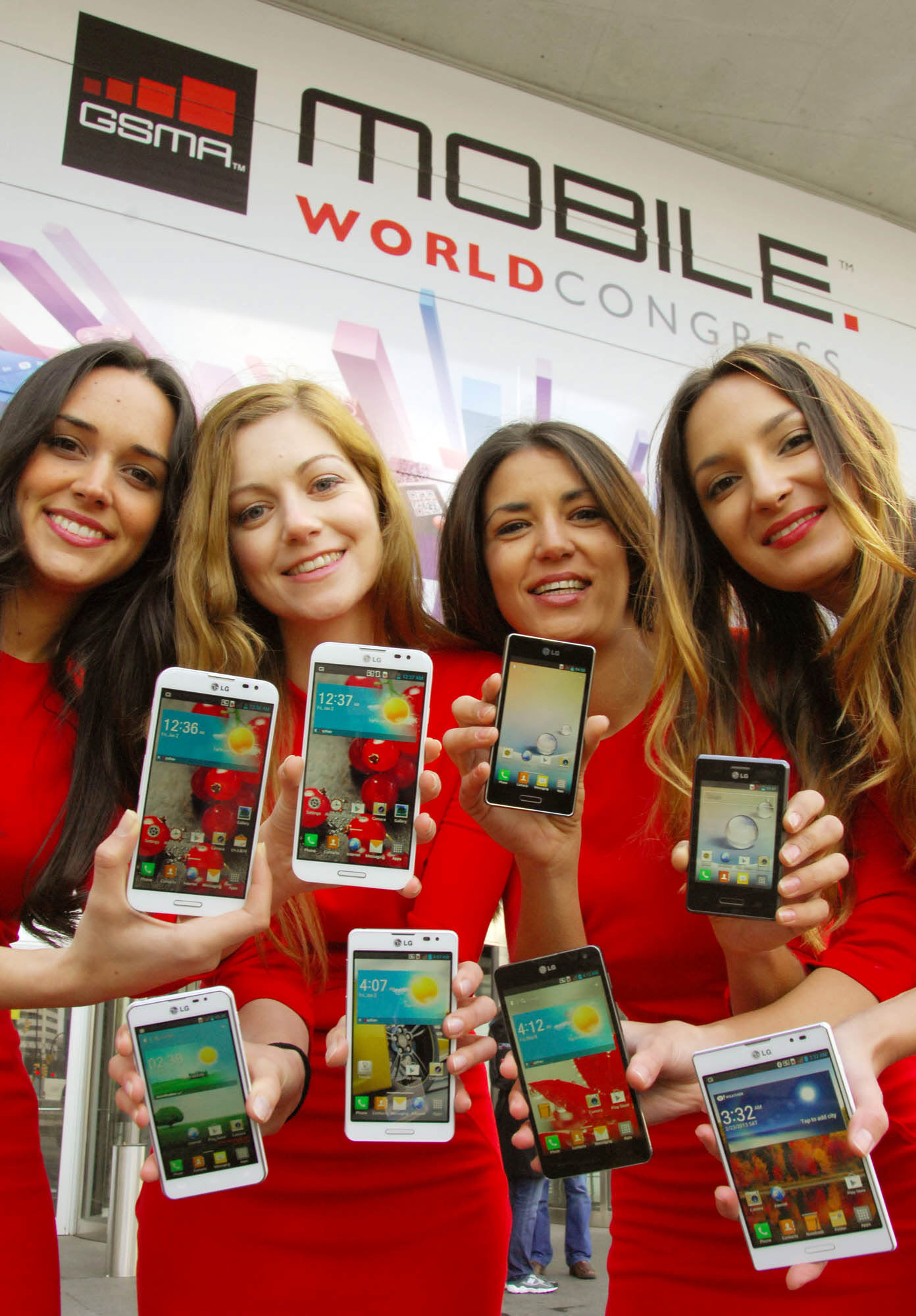 Four female models are smiling at a camera holding various strategic Optimus series devices at MWC 2013 - G, Vu:, F and LII.