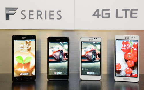 Four of new LG Optimus F series smartphones are displayed. From left to right; Optimus F7 in black color, Optimus F5 in black color, Optimus F5 in white color, Optimus F7 in white color. A panel saying “F SERIES 4G LTE” is also attached to the wall behind the handsets.