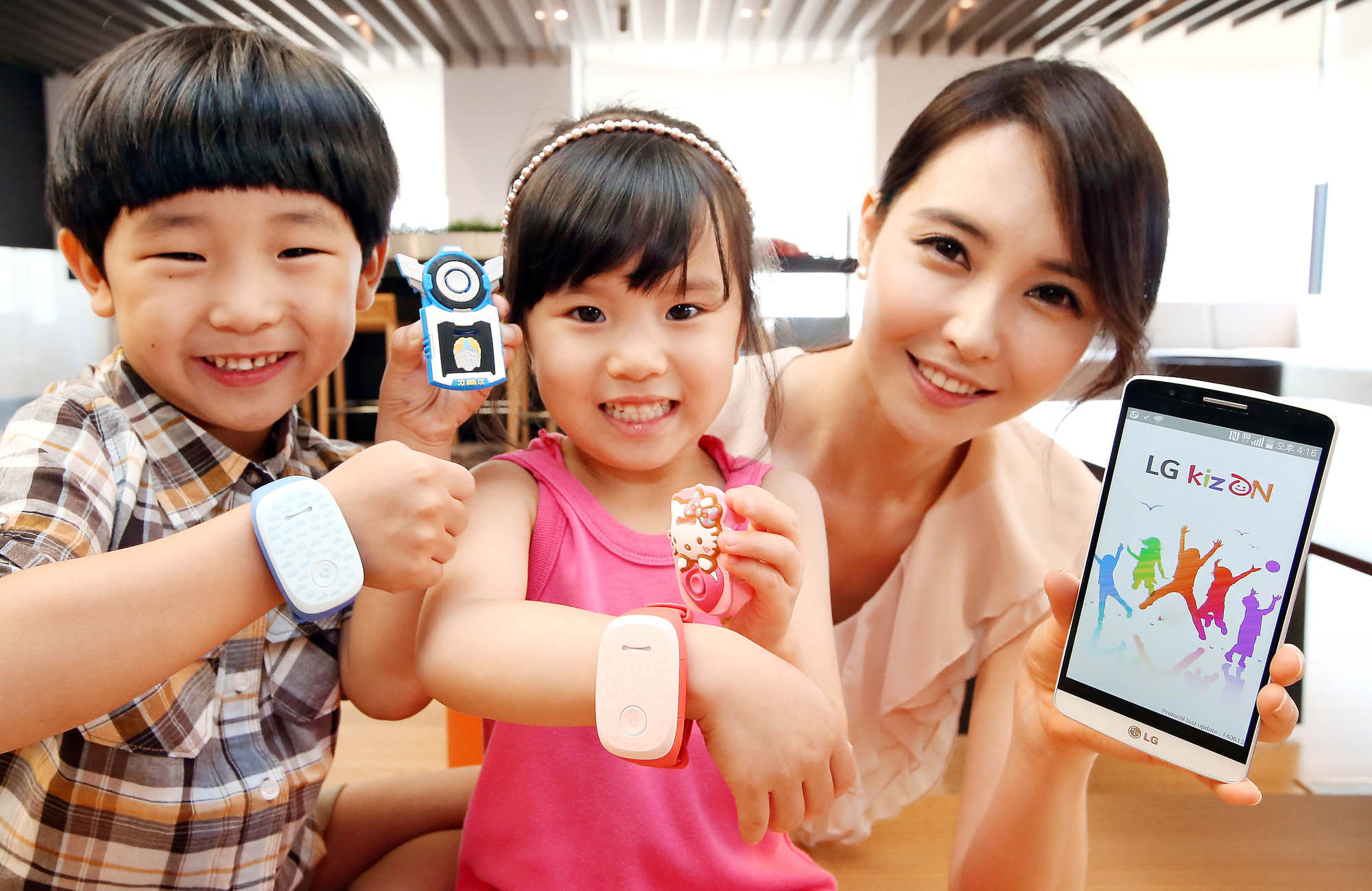 Two kid models wearing LG KizONS and a female model holding LG G3 are smiling at a camera.