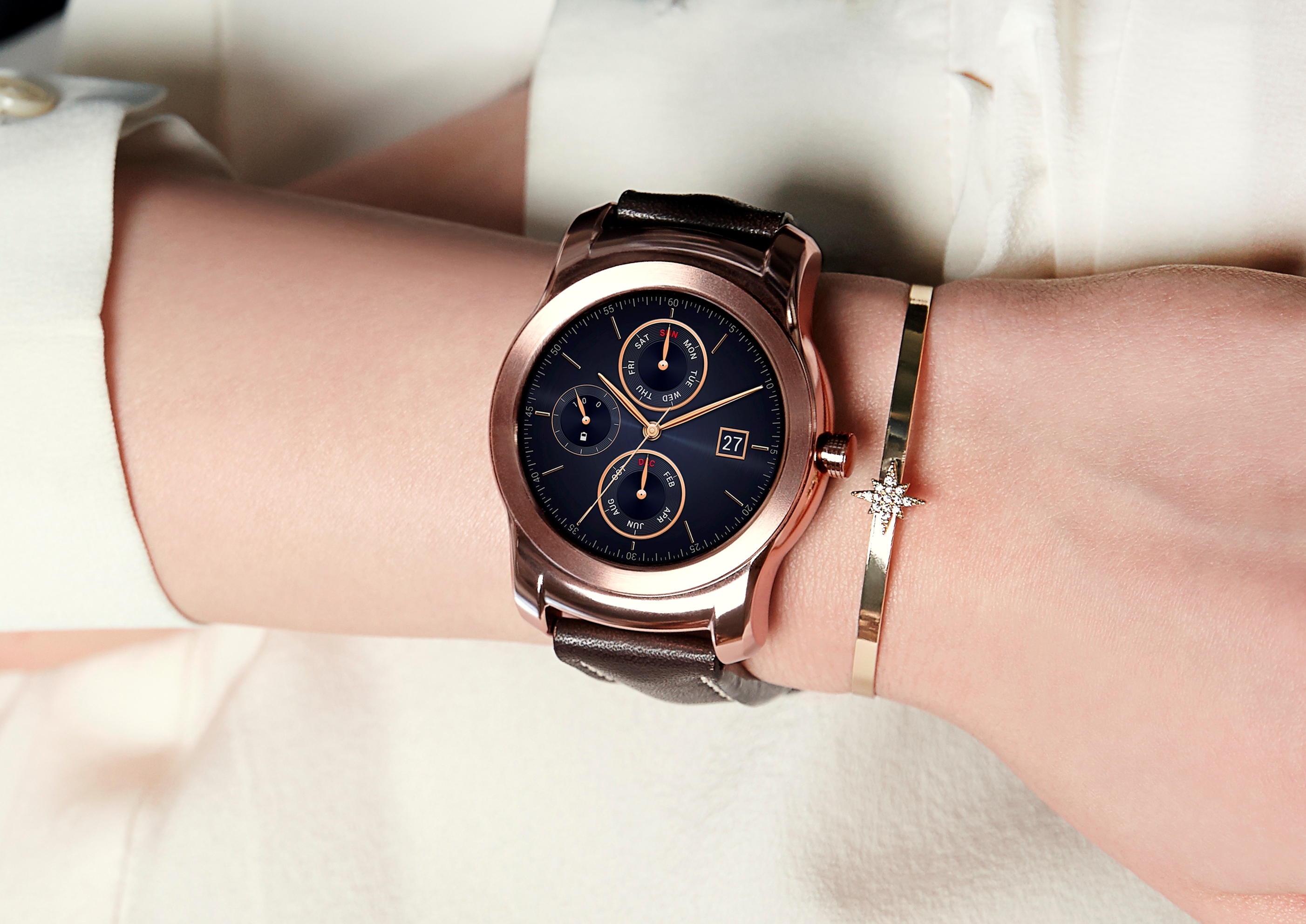 A close-up of a woman’s wrist while wearing the Rose Gold LG Watch Urbane and a matching gold bracelet.