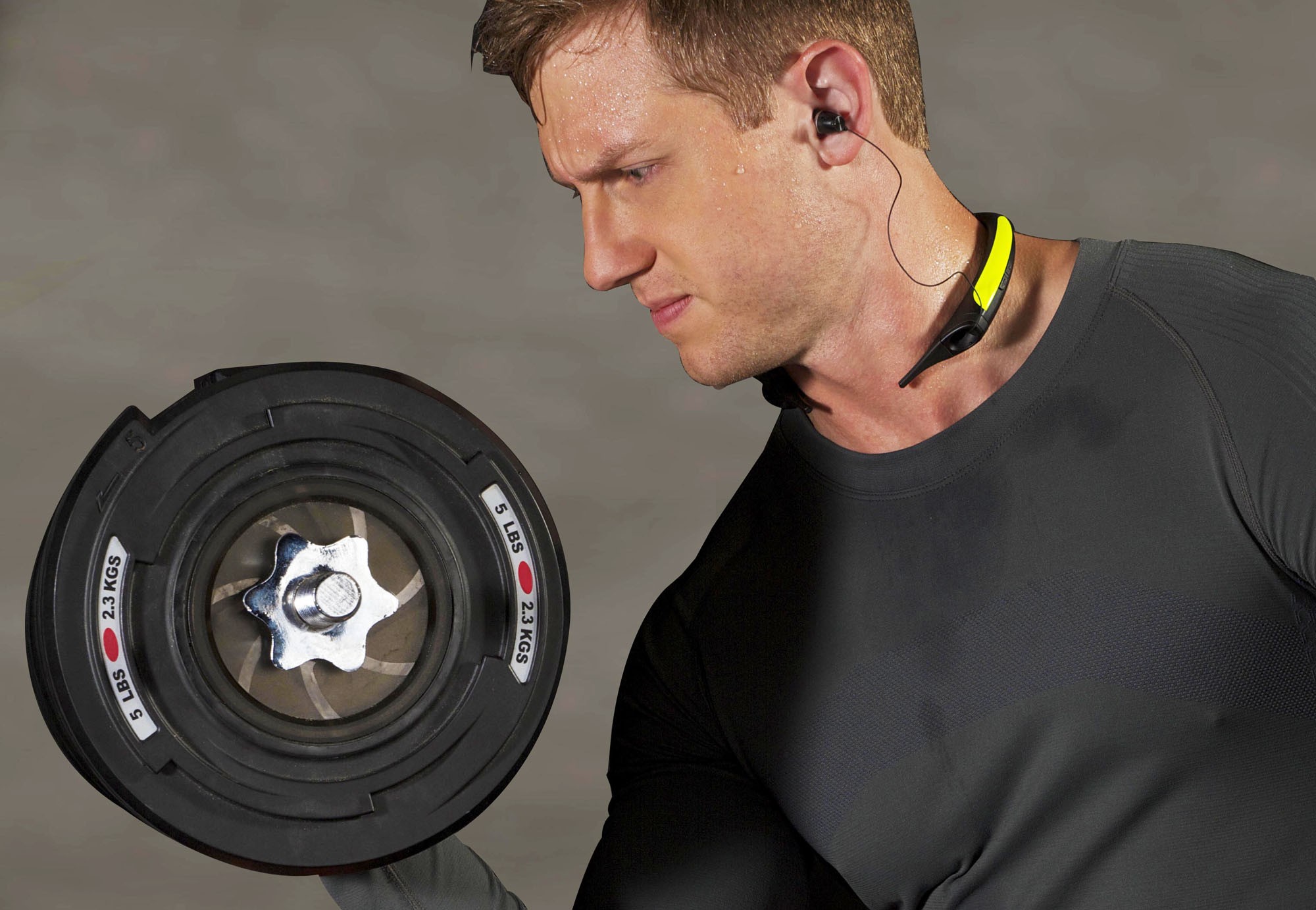 A man working out with a dumbbell while wearing the LG TONE Active.
