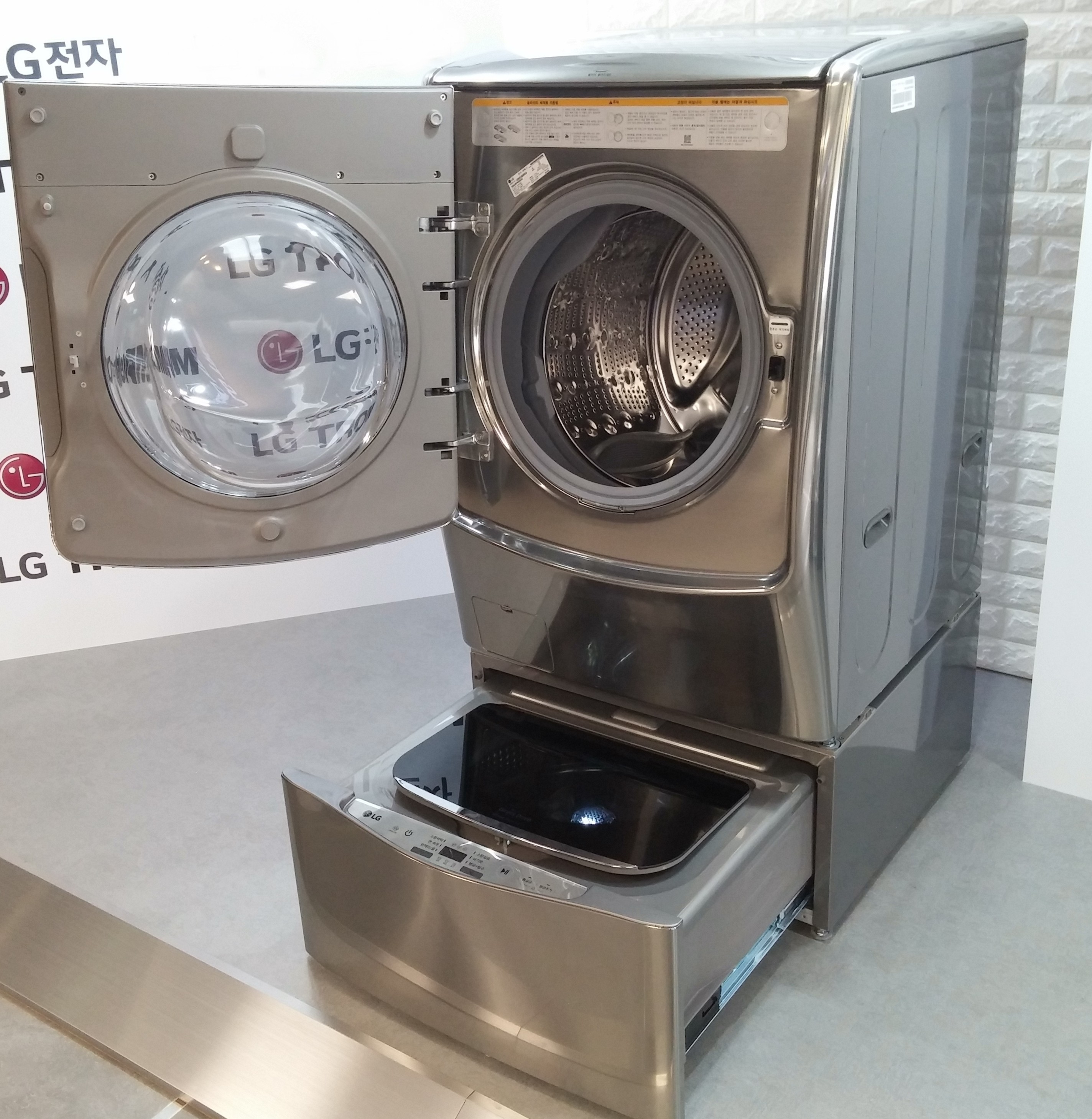LG TWINWash™ washing machine in gray color with front-load on the top and top-load at the bottom. Both washers are opened.