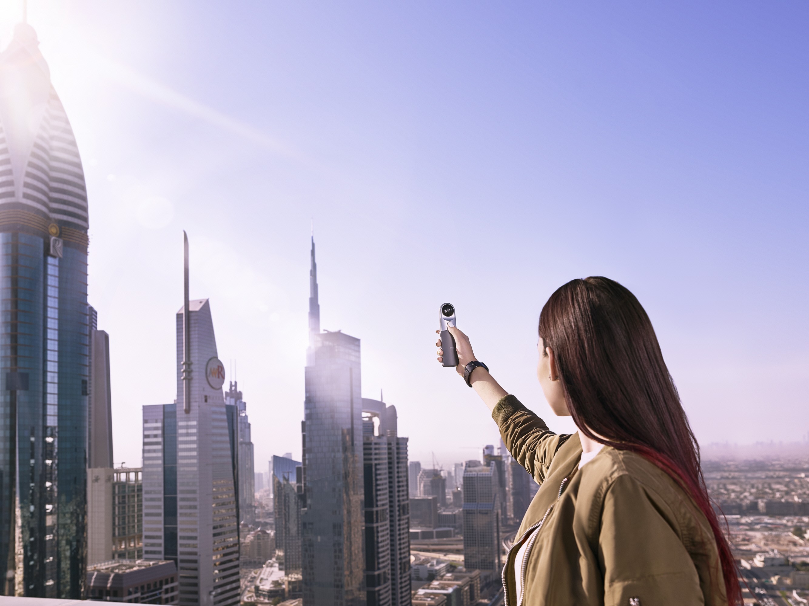 A woman is taking a picture of the skyscrapers in Dubai, United Arab Emirates, with the LG 360 CAM