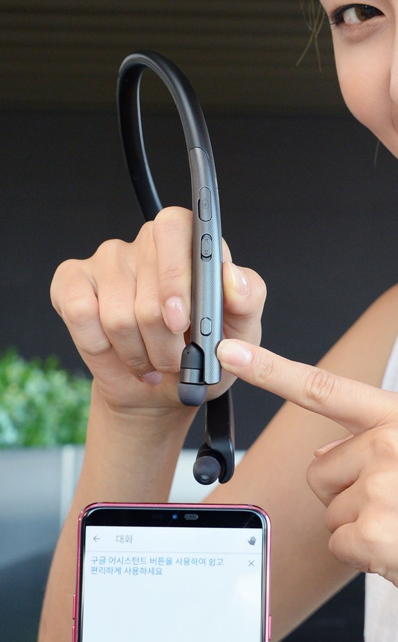 A woman pointing at the Google Assistant button on the LG TONE Platinum SE in her hands