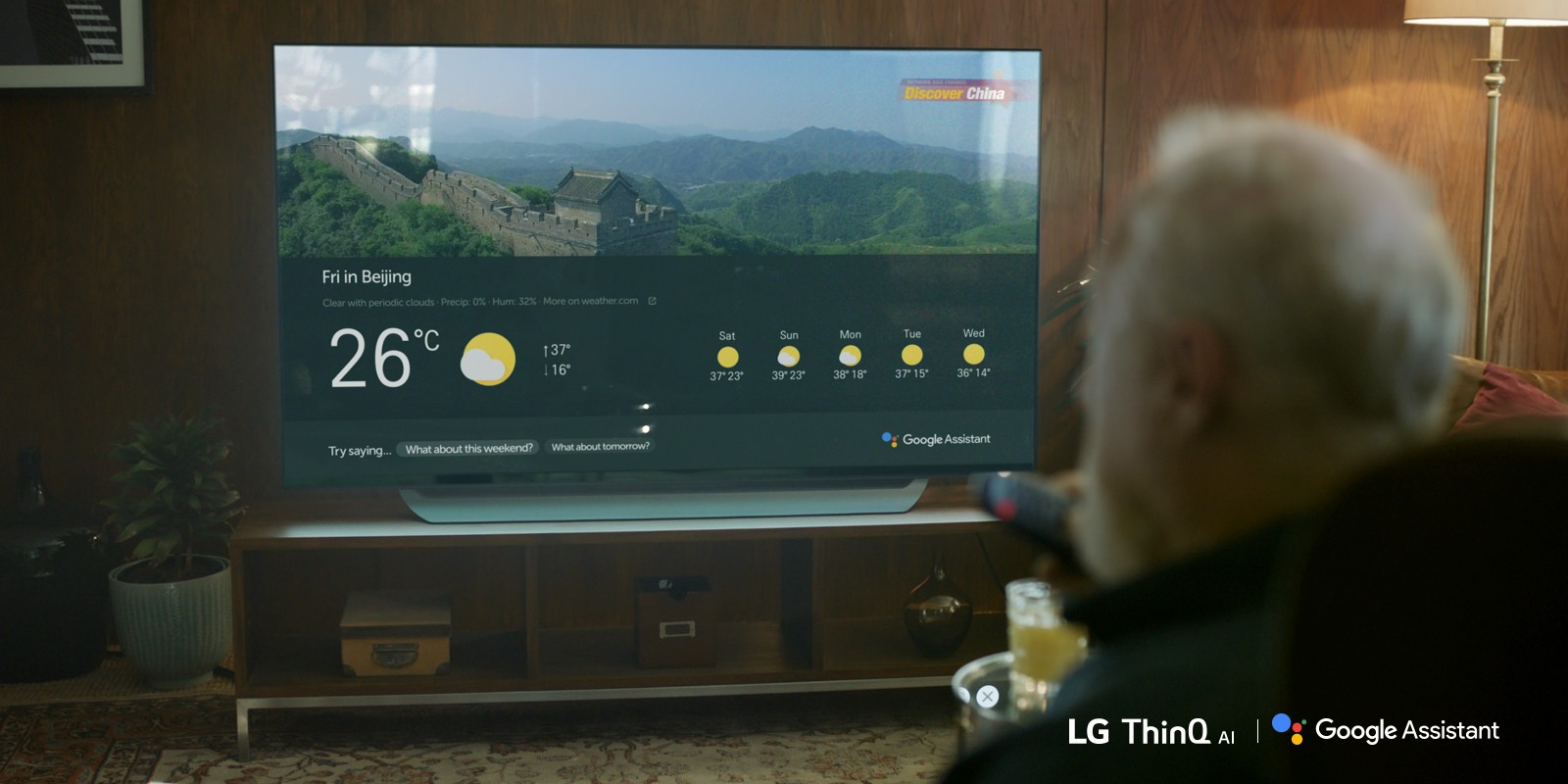 A man using Google Assistant on an LG TV with a remote control to check the weather