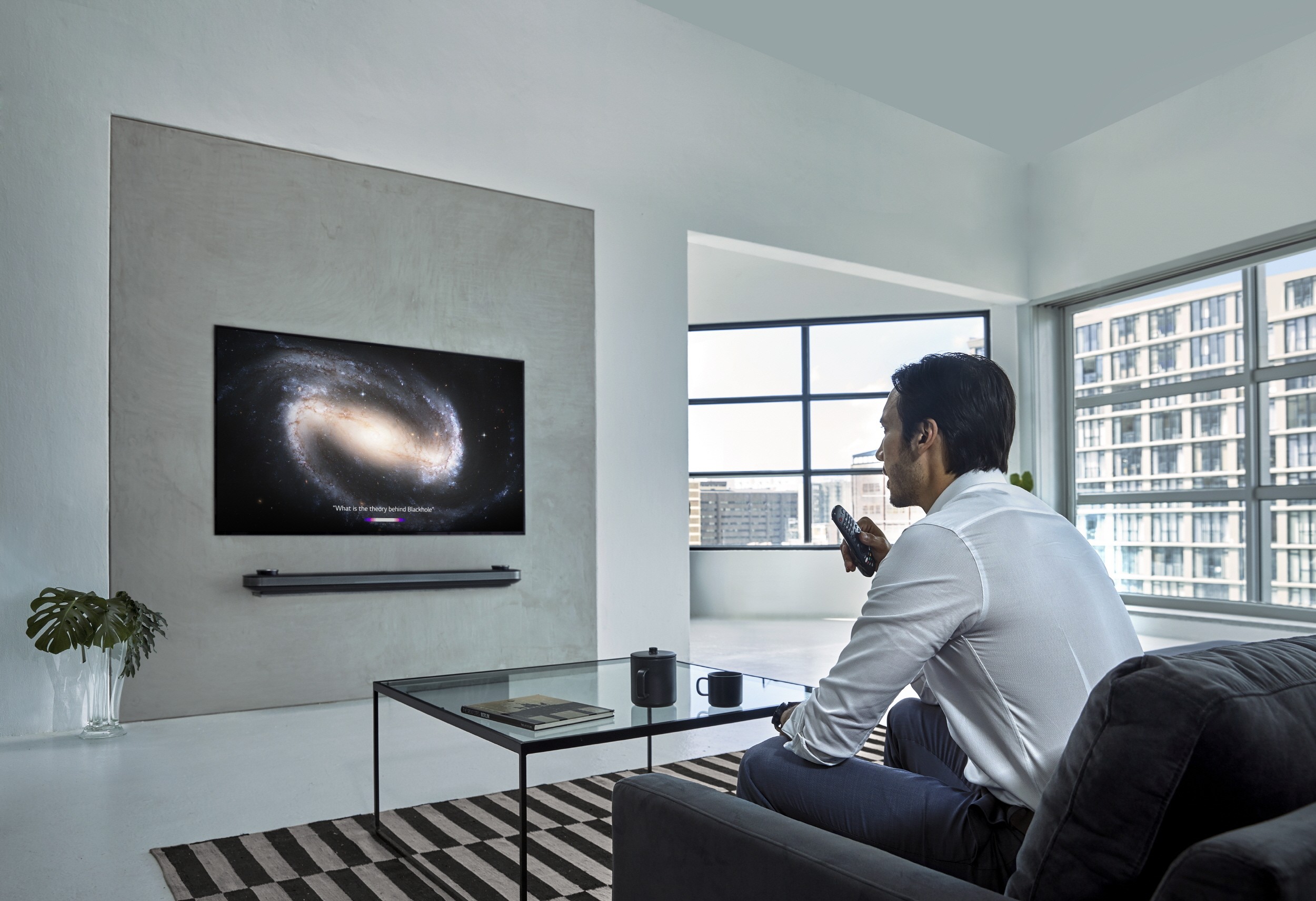 A man watching his LG OLED TV with a remote in one hand at his home