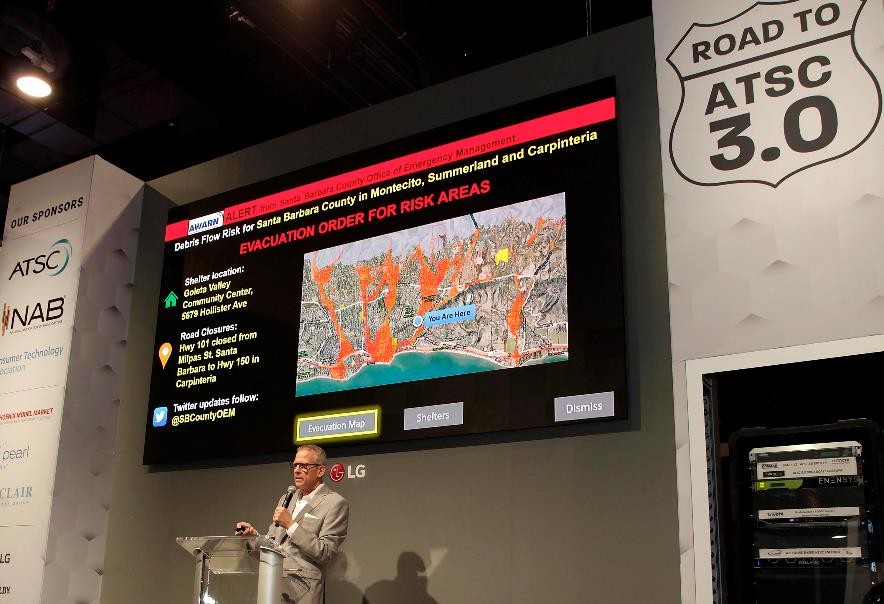 LG’s large display hangs against the wall over the podium for a presentation session during the Road to ATSC 3.0 exhibit event.