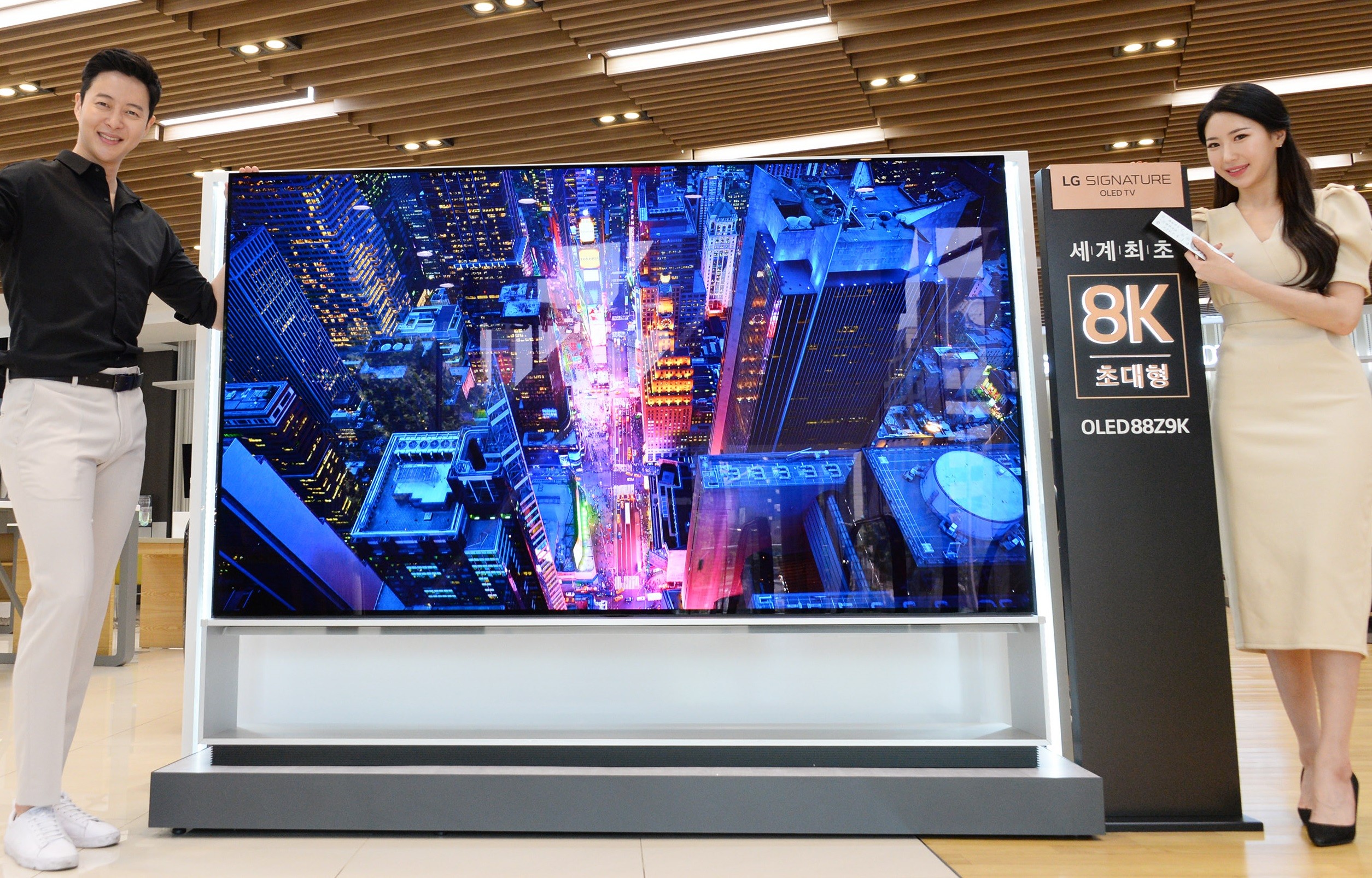 Two models demonstrating LG 8K OLED TV displaying skyscrapers