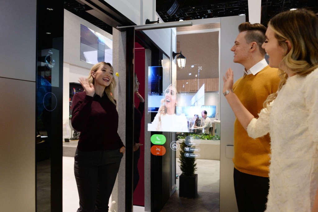 A woman waves to her friends after using LG ThinQ’s Smart Door concept which was showcased at CES 2020