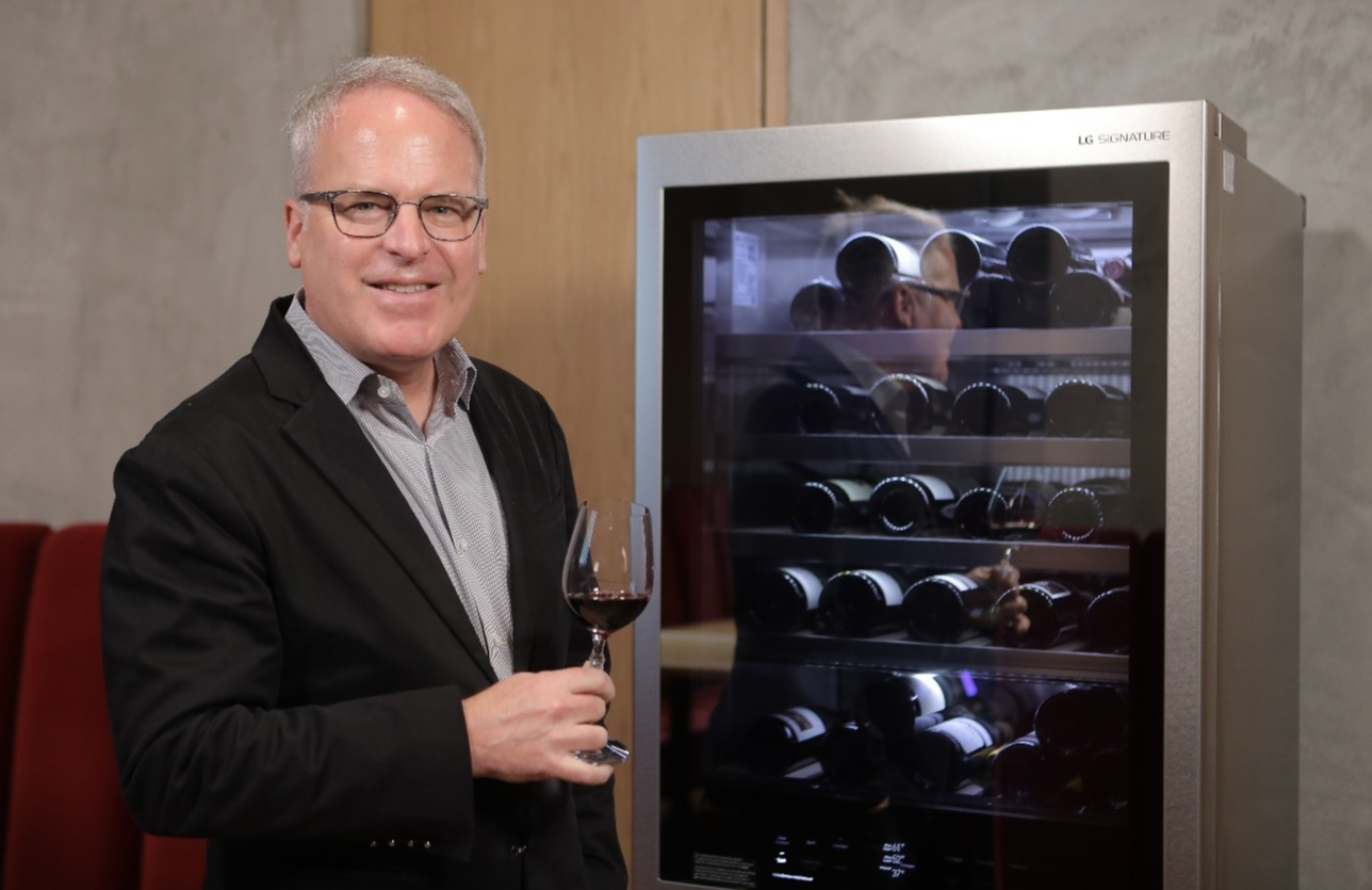 Wine critic and global brand ambassador James Suckling poses next to LG SIGNATURE wine cellar with a glass