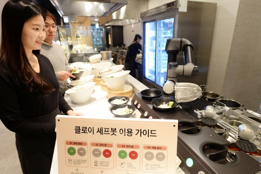 A man and women at a buffet being served their meals by LG ChefBot
