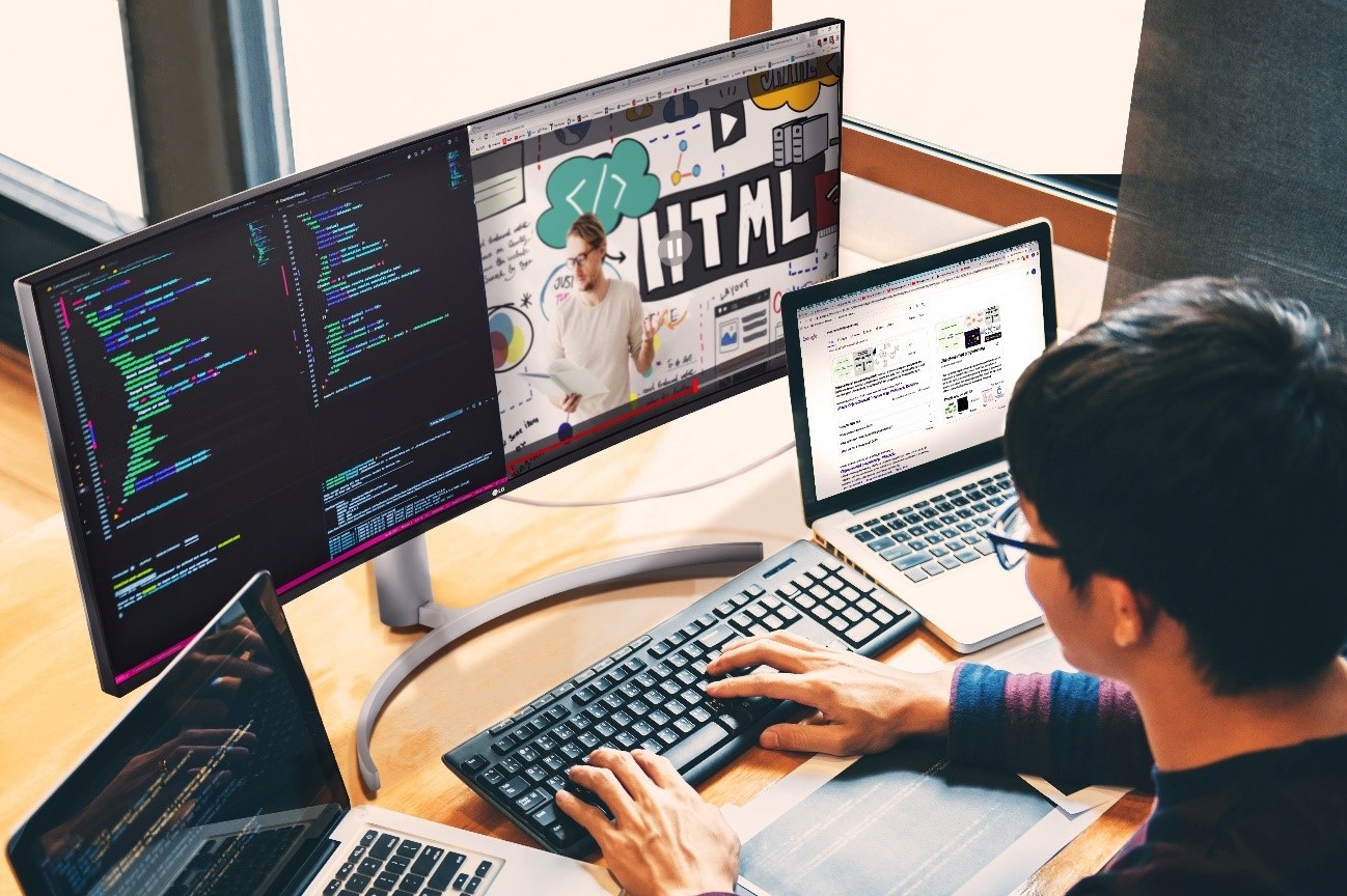 A computer programmer using the LG UltraWide Monitor with two laptops to multitask while working from home.