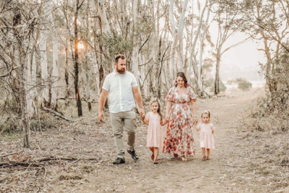 A family of four walking hand-in-hand through an Australian forest that has been ravaged by one of last year’s bush fires.