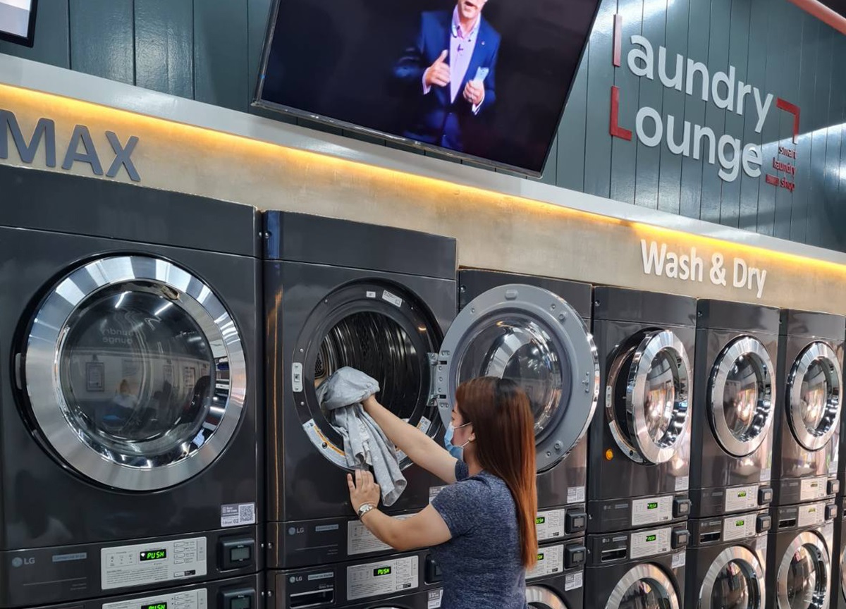 A woman is putting laundry into dryer at Laundry Lounge.